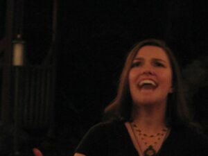 Ren Zatopek sings into the darkness, her head tipped back, her eyes intense. A blurry, mid-ritual photo with palpable energy.